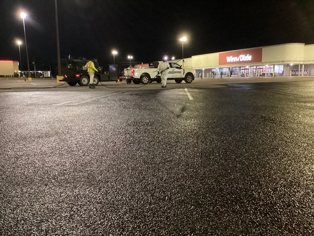 Wet parking lot pavement at night by Landmark Paving showcasing weather impact on asphalt performance