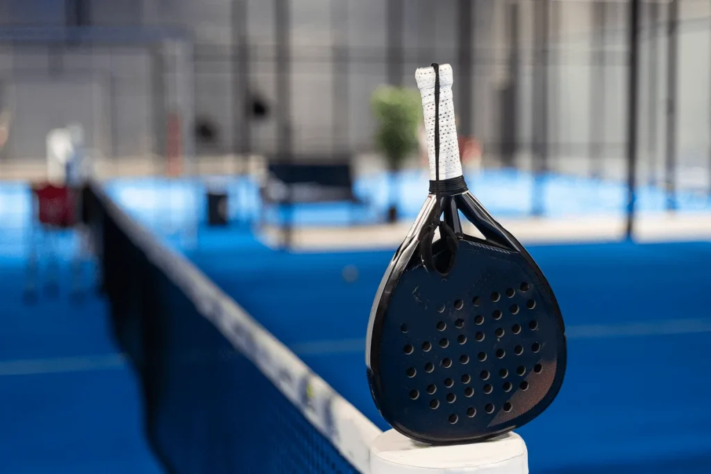 Padel racket and ball resting on a blue padel court built with Landmark Paving sports construction services.