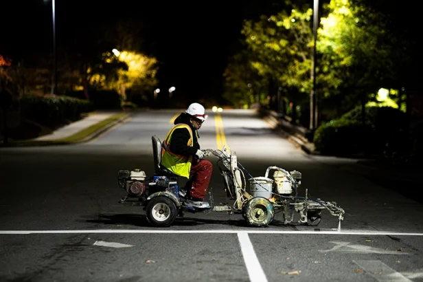 Landmark Paving crew performing pavement markings and line striping on a commercial roadway at night