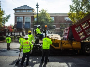 Commercial asphalt paving crew installing fresh pavement outside a retail shopping center
